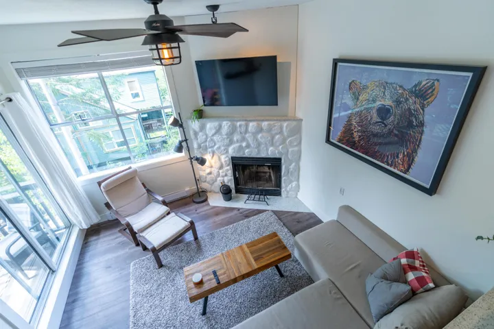 Living area featuring wood finished floors, a fireplace with flush hearth, a ceiling fan, and baseboards
