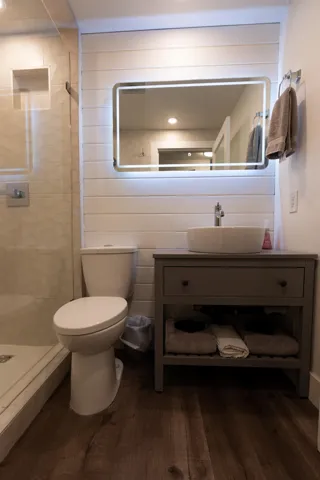 Full bath with wood finished floors, tiled shower, toilet, and vanity