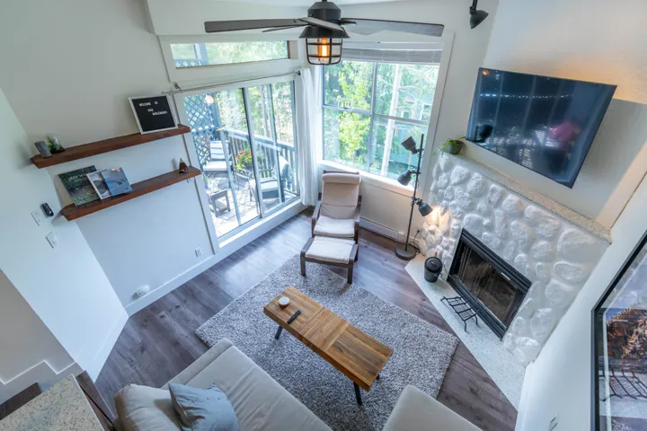 Living area with ceiling fan, a glass covered fireplace, wood finished floors, and baseboards