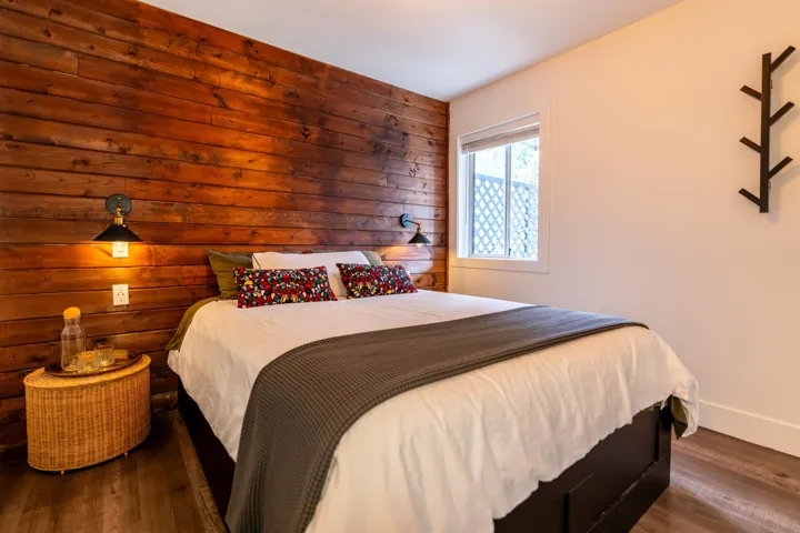 Bedroom featuring wood finished floors, wooden walls, and baseboards