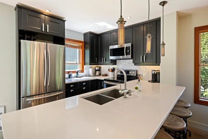 Kitchen with stainless steel appliances, a peninsula, backsplash, a breakfast bar area, and decorative light fixtures
