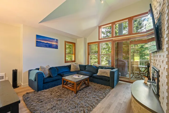 Living room with light wood-type flooring, a fireplace, and vaulted ceiling