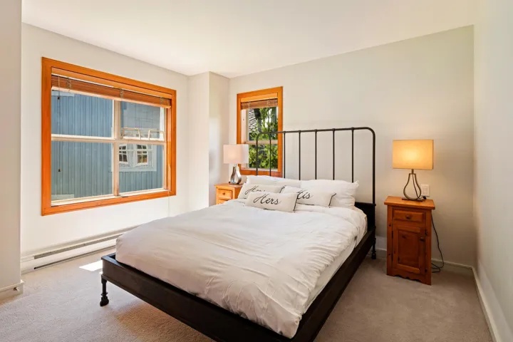 Bedroom with light colored carpet and baseboard heating