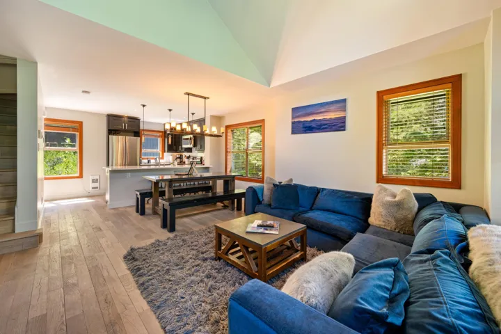 Living area featuring light wood finished floors, healthy amount of natural light, a chandelier, and vaulted ceiling