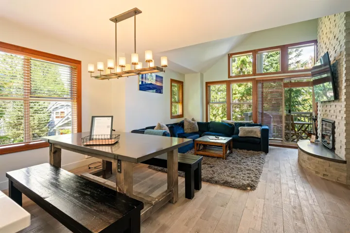 Dining space with light wood-style flooring, plenty of natural light, a fireplace, vaulted ceiling, and a chandelier