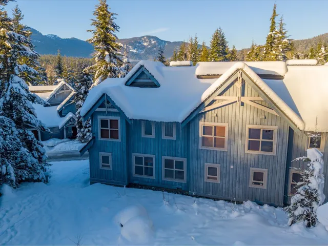 Snow covered property with a mountain view and board and batten siding