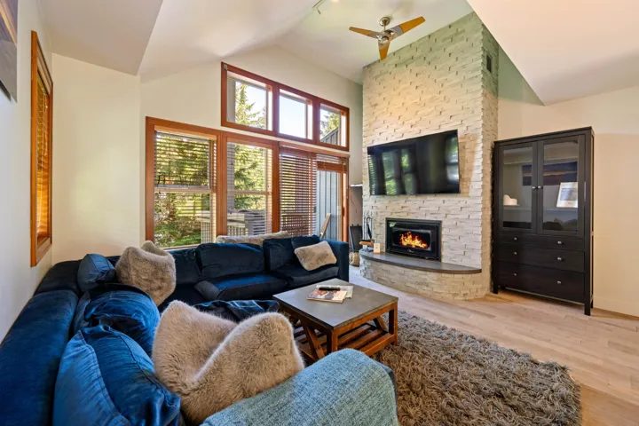 Living room featuring light wood-style floors, vaulted ceiling, a fireplace, and ceiling fan