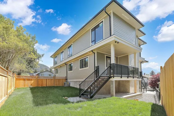 Rear view of property featuring a fenced backyard and stairs