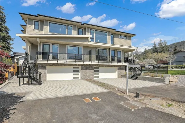 View of front of property with stairs, an attached garage, decorative driveway, and a balcony