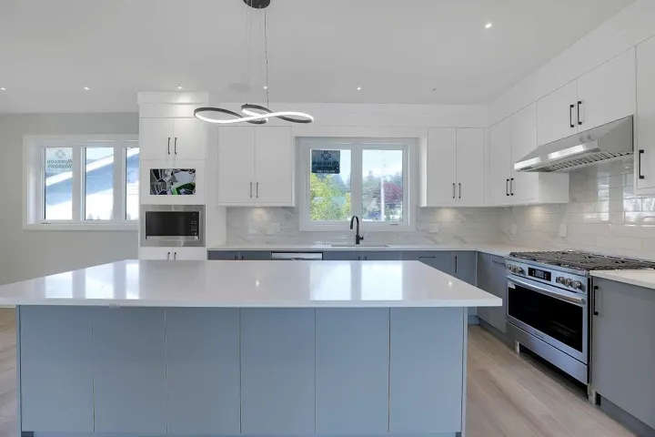 Kitchen with appliances with stainless steel finishes, decorative backsplash, decorative light fixtures, under cabinet range hood, and gray cabinetry