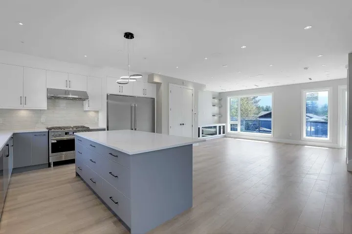 Kitchen featuring backsplash, gray cabinets, stainless steel appliances, hanging light fixtures, and a kitchen island