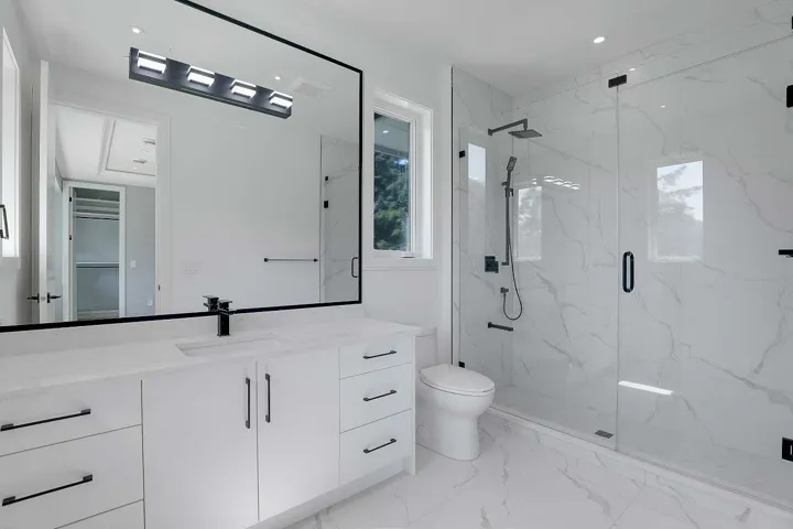 Bathroom featuring light marble finish flooring, vanity, and a marble finish shower