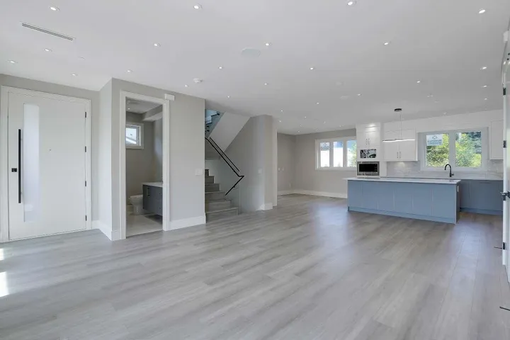 Unfurnished living room featuring plenty of natural light, light wood-style flooring, stairs, and recessed lighting