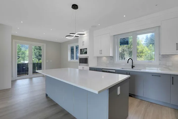 Kitchen featuring gray cabinetry, light wood-style flooring, decorative light fixtures, light stone counters, and recessed lighting