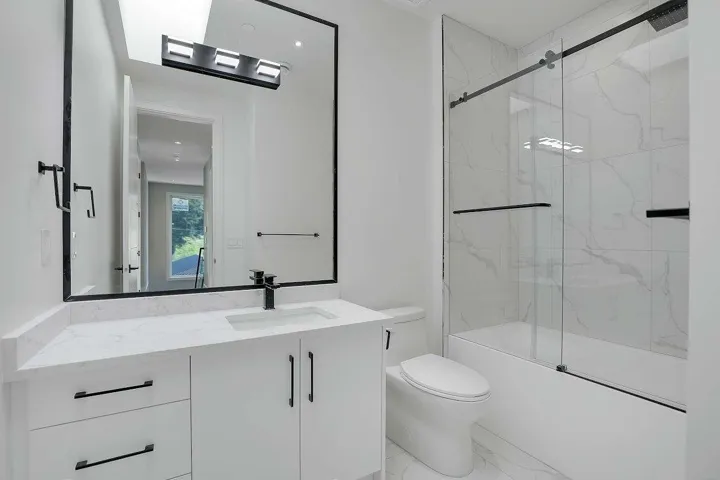 Bathroom featuring vanity, enclosed tub / shower combo, and marble finish flooring
