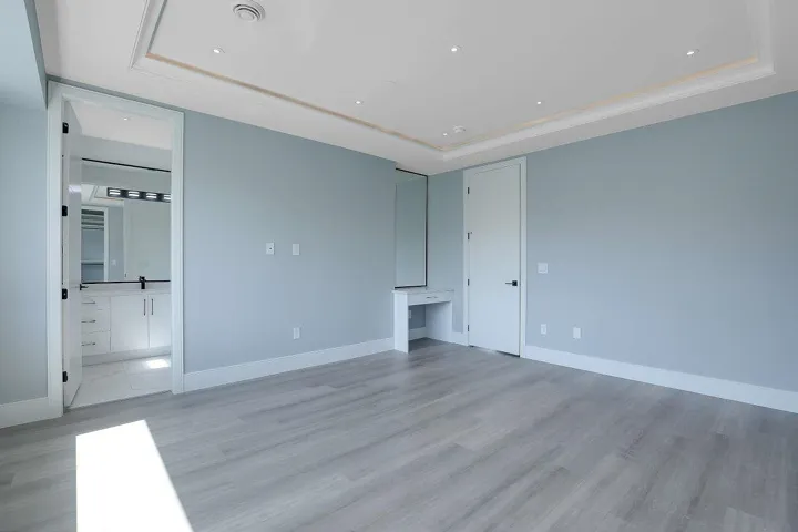 Unfurnished living room with a raised ceiling, light wood-type flooring, built in study area, and recessed lighting