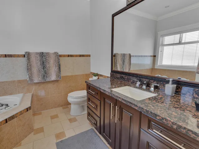 Bathroom featuring a dark wood vanity with a stone countertop, an integrated sink, and a large framed mirror