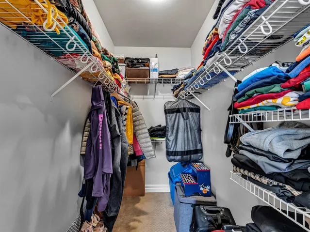 Walk-in closet featuring white wire shelving and hanging rods