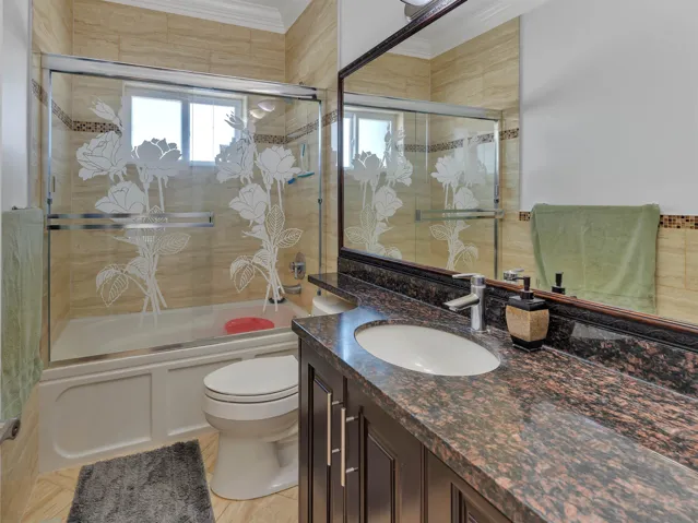 Bathroom featuring a dark wood-finish vanity with a brown speckled countertop, an undermount sink, and a chrome faucet