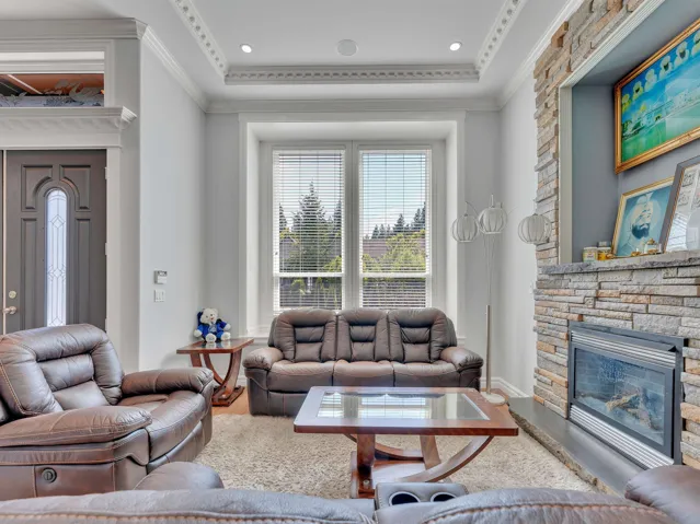Living space featuring a stone-clad fireplace with an integrated electric insert, recessed ceiling lighting, and detailed crown molding