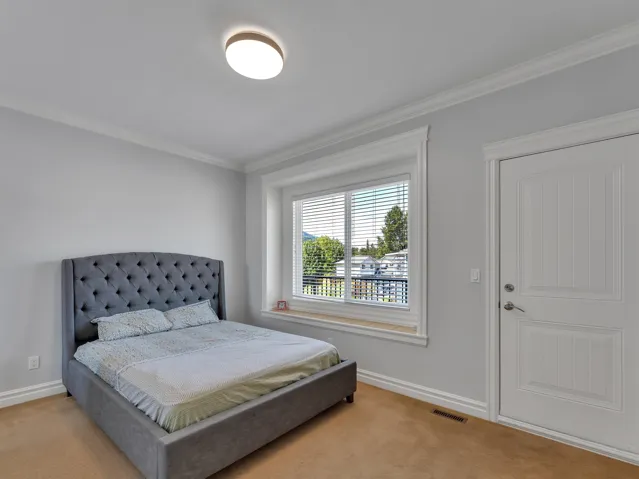 Neutral-toned room featuring a large window with white blinds, crown molding, a paneled door with brushed nickel hardware, and light-colored wall paint
