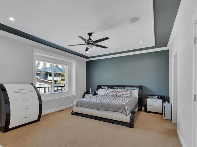 Spacious room featuring a tray ceiling with recessed lighting and a ceiling fan