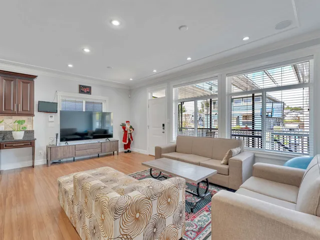 Open-concept living space with wood-finish flooring, recessed lighting, and crown molding