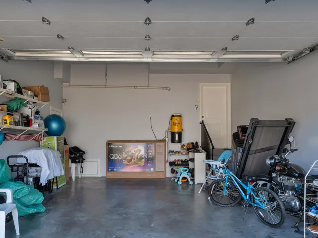 Spacious garage featuring a concrete floor, overhead fluorescent lighting, interior access door, and a built-in central vacuum system