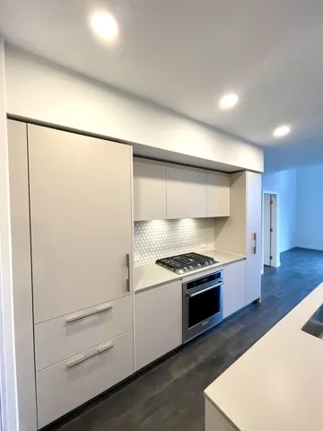 Kitchen featuring white cabinetry, light countertops, stainless steel appliances, modern cabinets, and backsplash