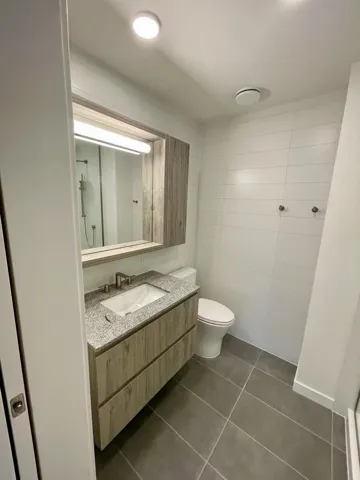 Full bath with vanity, dark tile patterned floors, and tile walls
