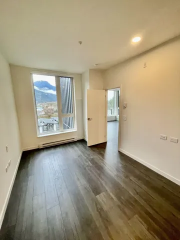 Empty room featuring a baseboard radiator, dark wood finished floors, a textured ceiling, and recessed lighting