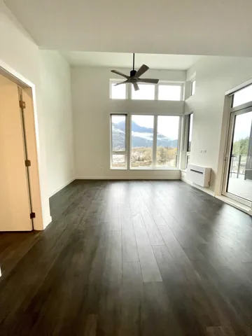 Unfurnished living room featuring plenty of natural light, ceiling fan, dark wood finished floors, and a mountain view
