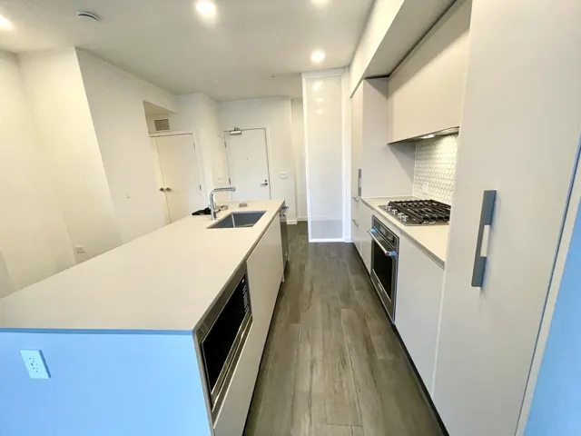 Kitchen with an island with sink, modern cabinets, stainless steel appliances, dark wood finished floors, and white cabinetry