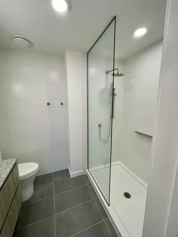 Full bathroom featuring vanity, dark tile patterned floors, a stall shower, and tile walls