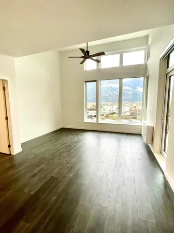 Unfurnished room featuring dark wood-style flooring and ceiling fan