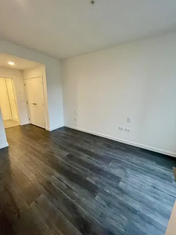 Spare room with dark wood-type flooring and baseboards
