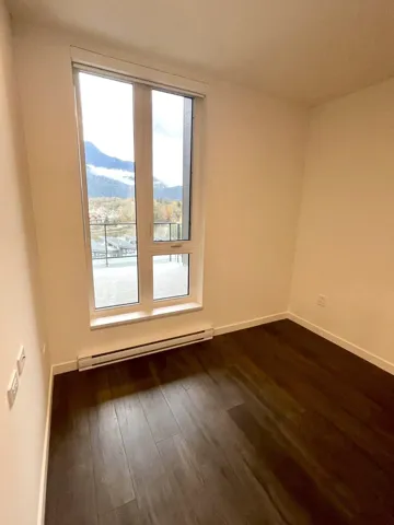 Empty room with a baseboard radiator and dark wood finished floors