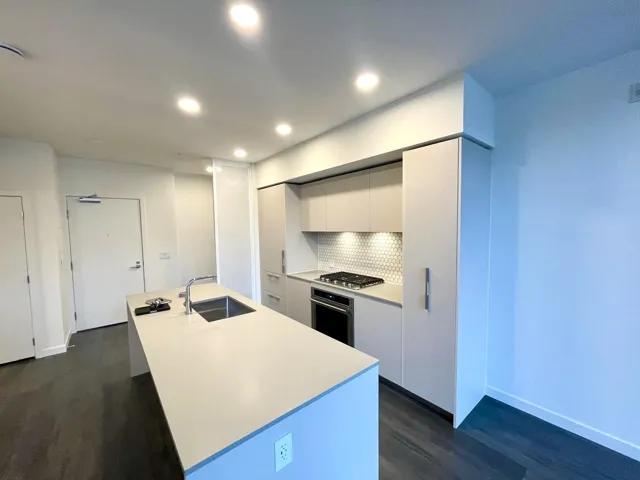 Kitchen with modern cabinets, a center island with sink, appliances with stainless steel finishes, white cabinetry, and backsplash