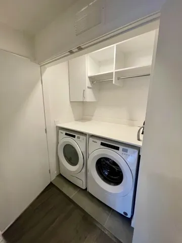 Washroom featuring washing machine and dryer, cabinet space, and dark wood finished floors