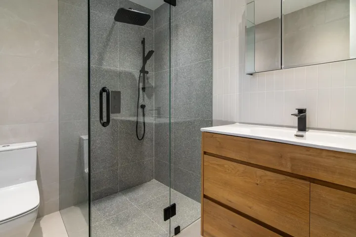 Bathroom featuring toilet, tile walls, and a shower stall