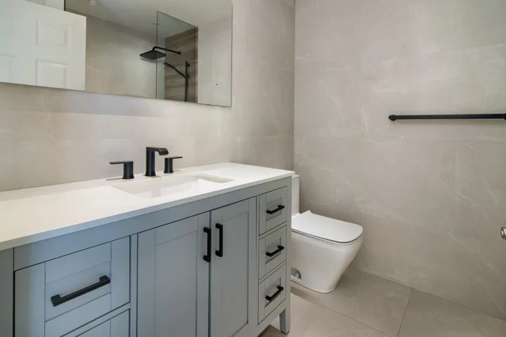 Bathroom with vanity, tile patterned flooring, walk in shower, toilet, and tile walls