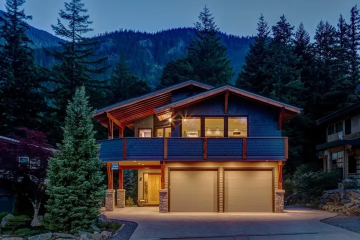 View of front of home with a balcony, driveway, a garage, stone siding, and a mountain view