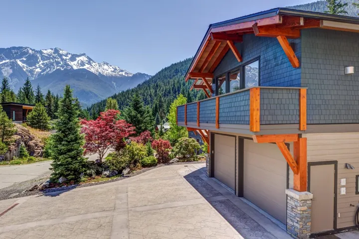 View of side of property with a balcony, a mountain view, driveway, and an attached garage