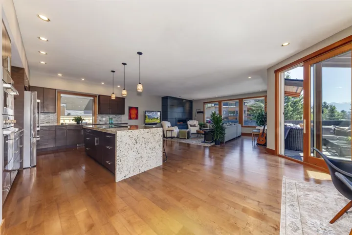 Kitchen with stainless steel appliances, wood finished floors, a kitchen island, open floor plan, and a kitchen breakfast bar