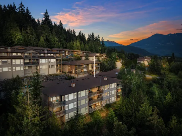 Multi-story residential buildings nestled into a wooded hillside