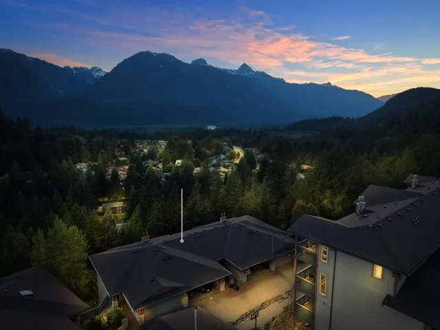 Aerial perspective showcasing a residential building with dark roofing and mountain scenery
