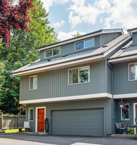 Vertical siding exterior with a prominent single-car garage and a vibrant orange entry door