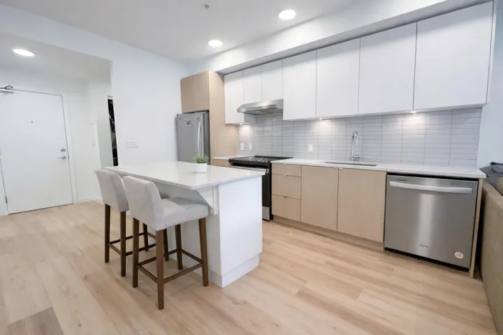 Kitchen featuring white cabinets, stainless steel appliances, a kitchen bar, modern cabinets, and light wood-style floors
