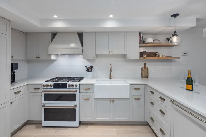 Kitchen featuring light countertops, double oven range, a sink, and premium range hood