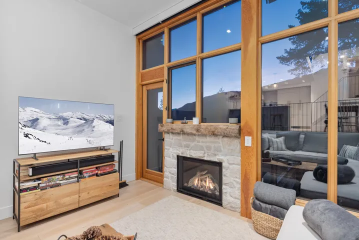 Living area featuring baseboards, a stone fireplace, and wood finished floors